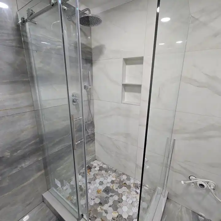 Glass shower with grey marble-look walls and a stone mosaic floor