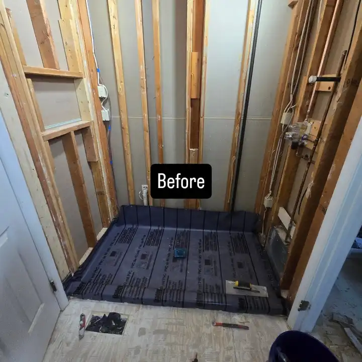 The same shower before work: bare studs and the old drain in the subfloor