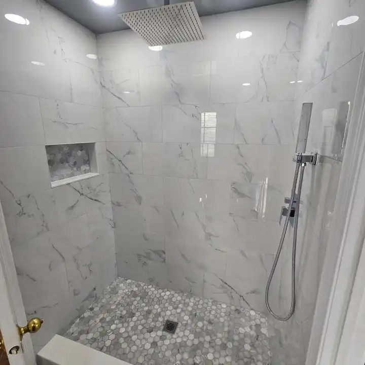 Shower plumbing wall with a recessed niche and black handheld shower
