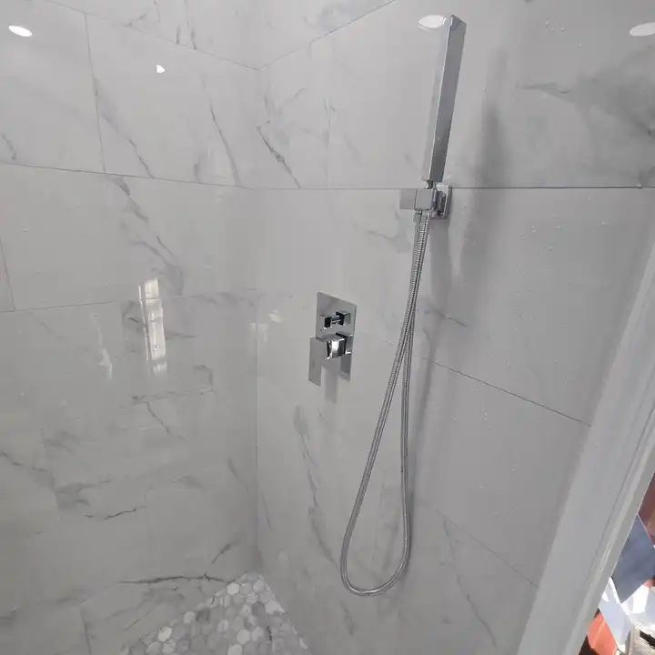 Marble-look shower wall with a black rain head and handheld on a slide bar