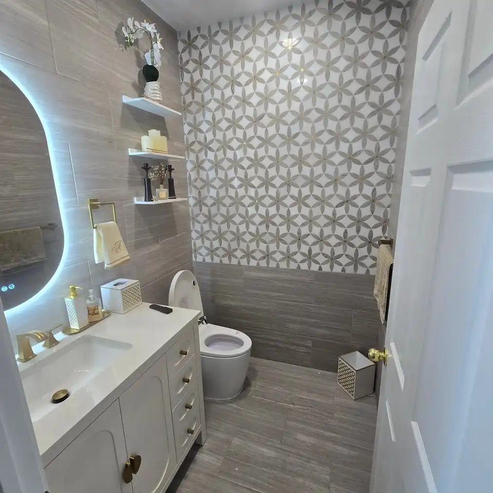 Patterned tile feature wall behind a backlit oval mirror and a white vanity