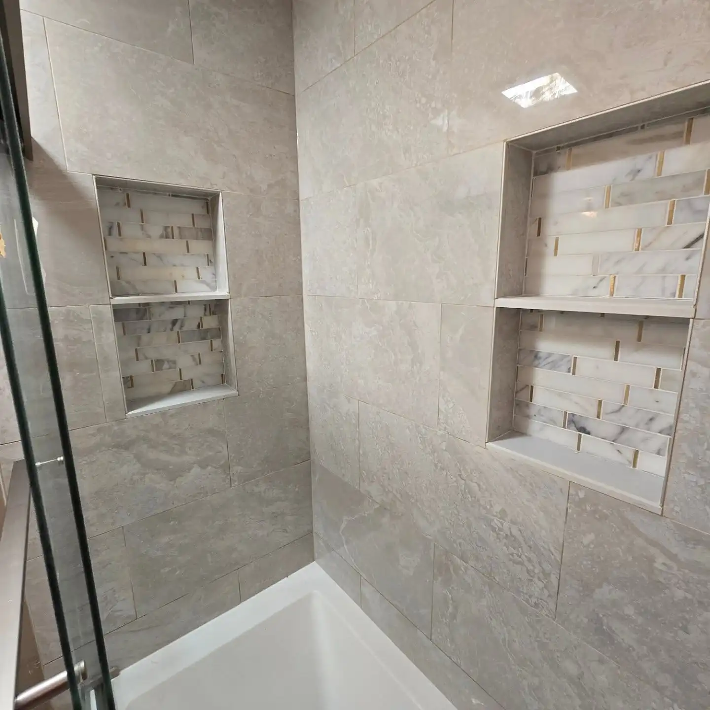 Two recessed niches with a stone mosaic back set into large-format tile — a detail from a recent job