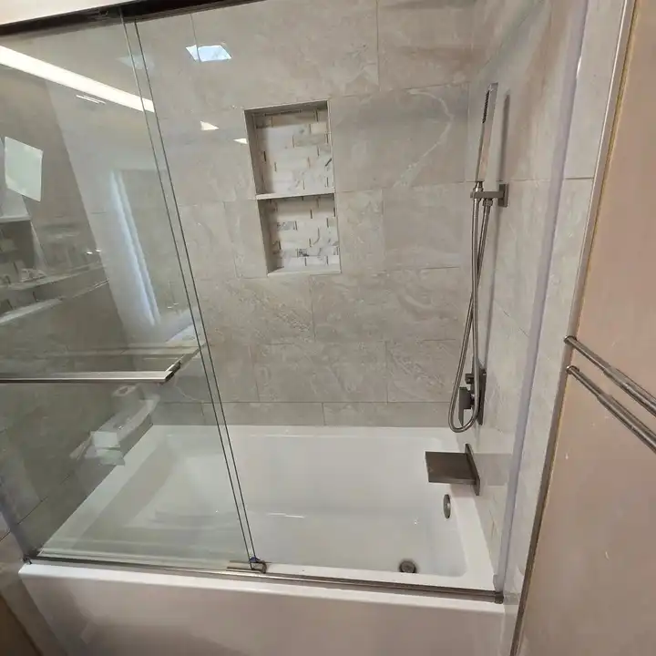 Tub surround with a frameless sliding door and two mosaic-backed niches