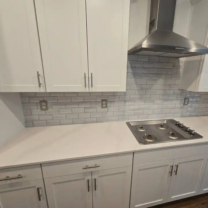 Grey subway tile meeting the quartz counter behind the gas cooktop