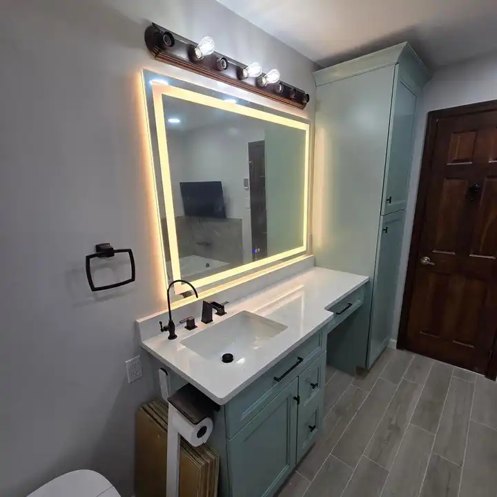 Green vanity with an LED mirror beside the bathroom door