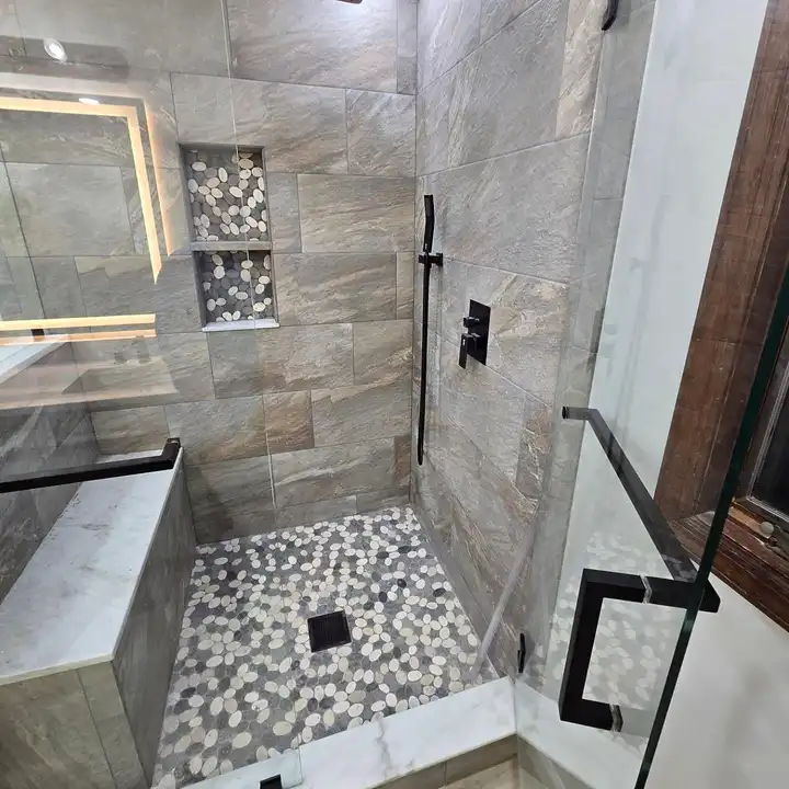 Pebble shower floor with black fixtures on a stone-look wall
