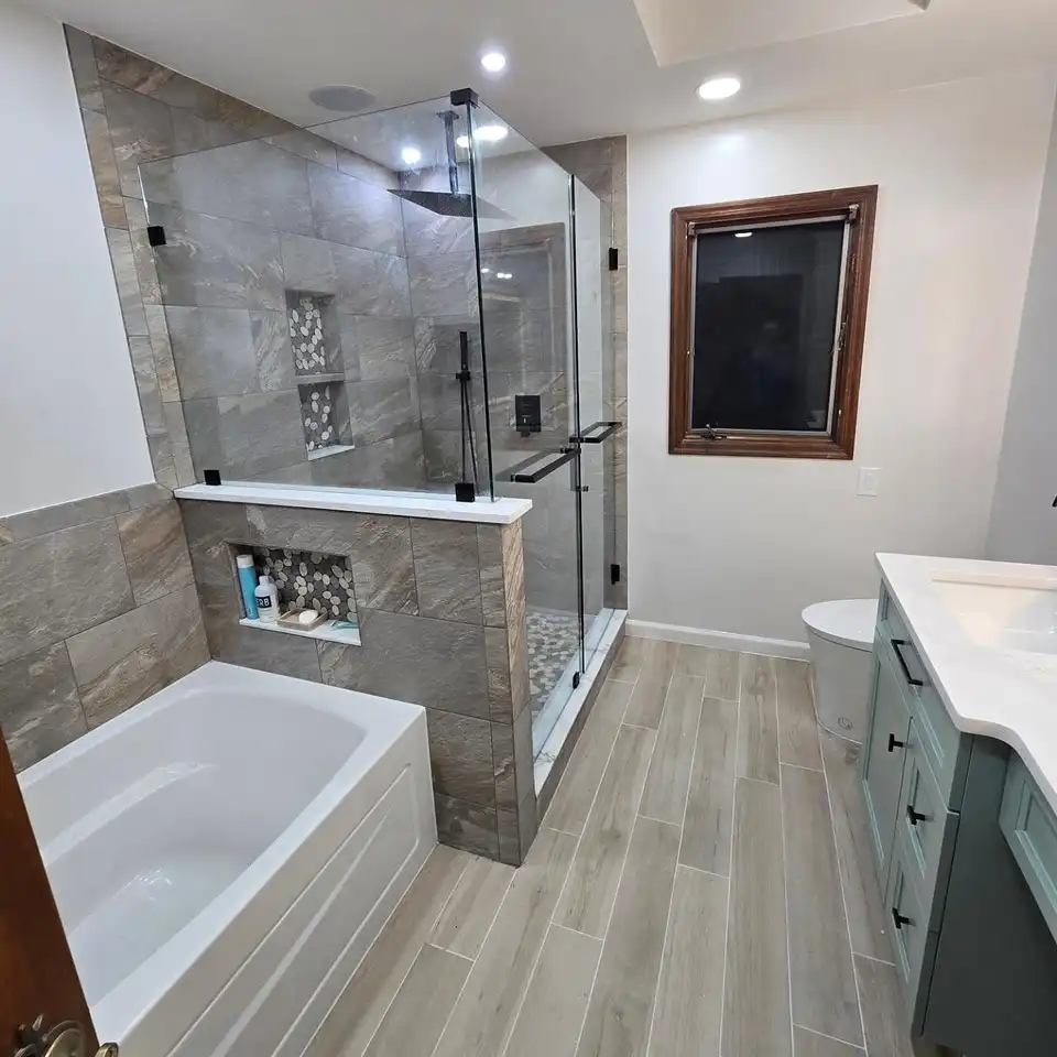 Bathroom with a tub, a separate glass shower and a wood-look plank floor