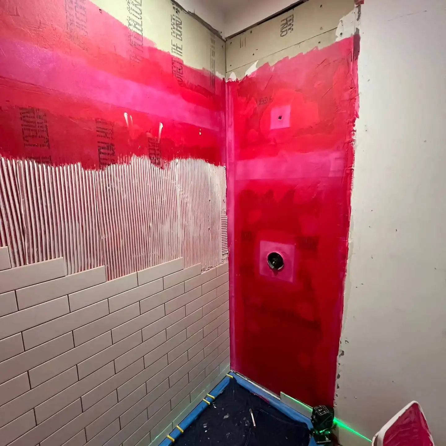 Shower walls and curb coated in red liquid waterproofing membrane