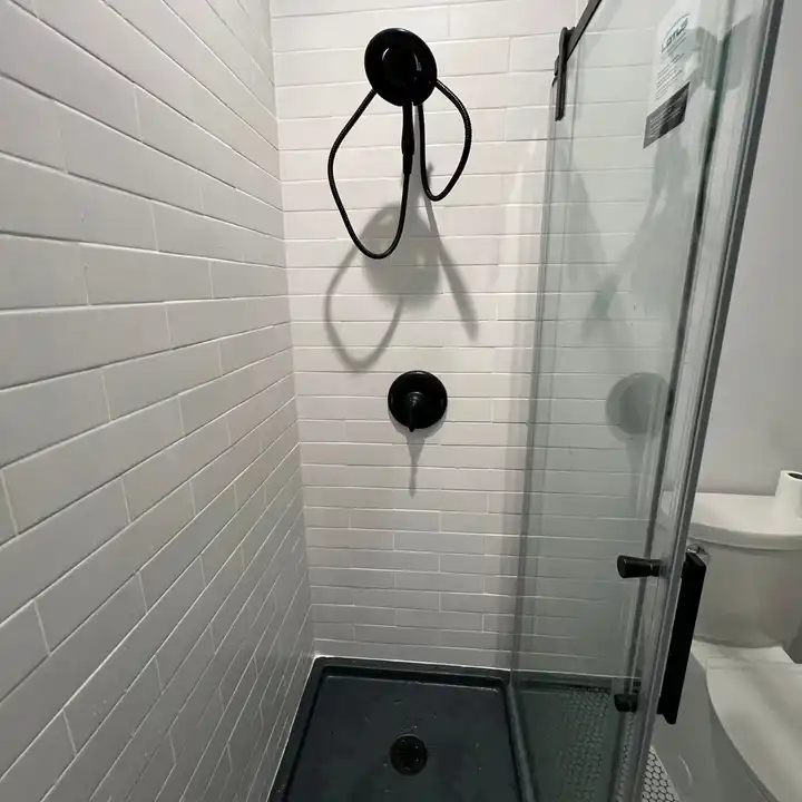 Matte black handheld shower on white subway tile, black grout line