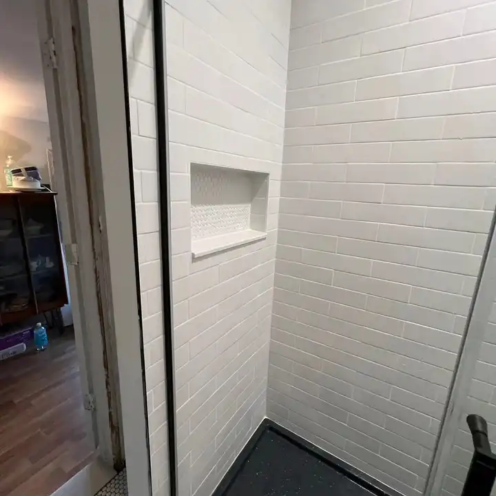 Recessed niche in white subway tile with a dark slate-look floor below