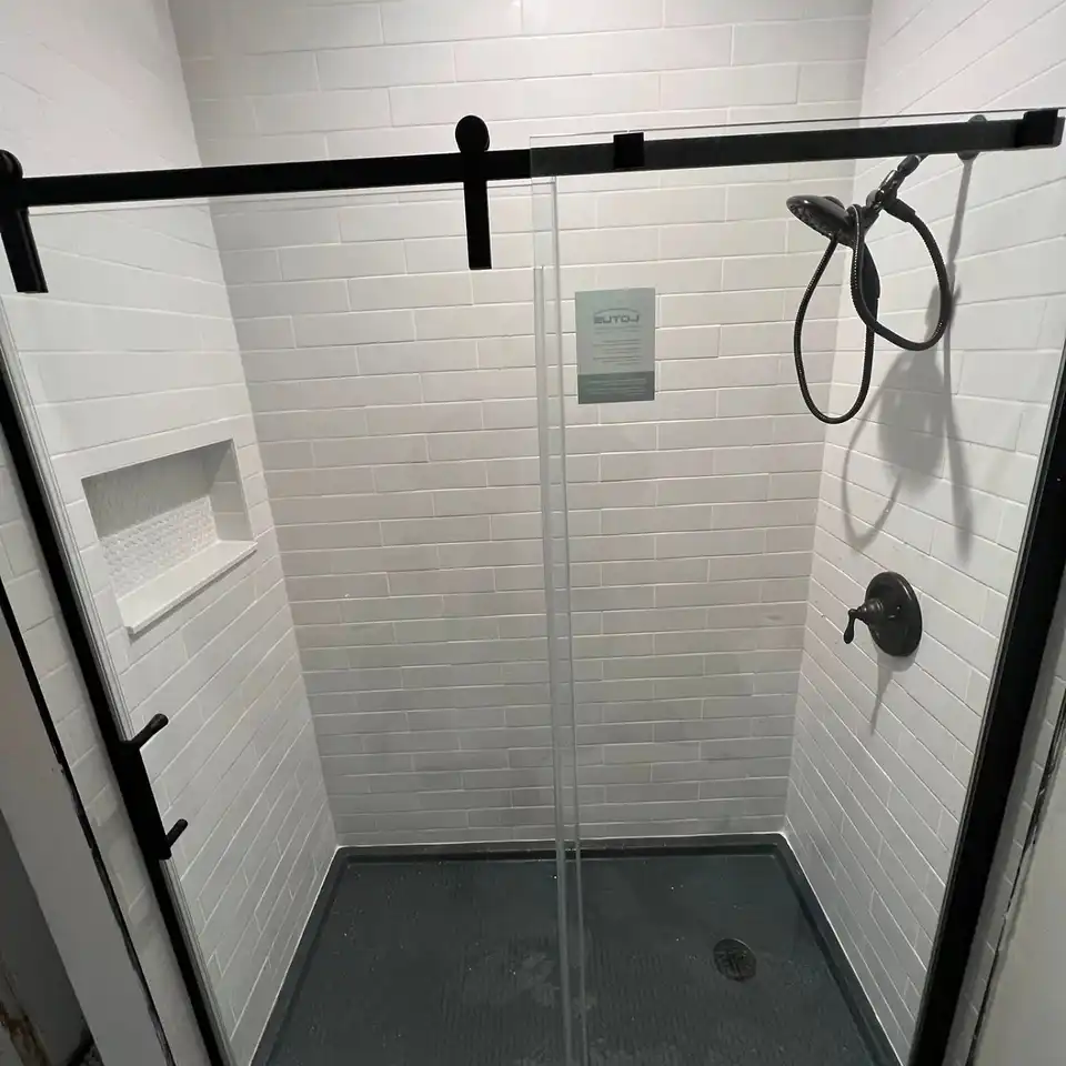 White subway tile shower with a black-framed sliding glass door and black fixtures