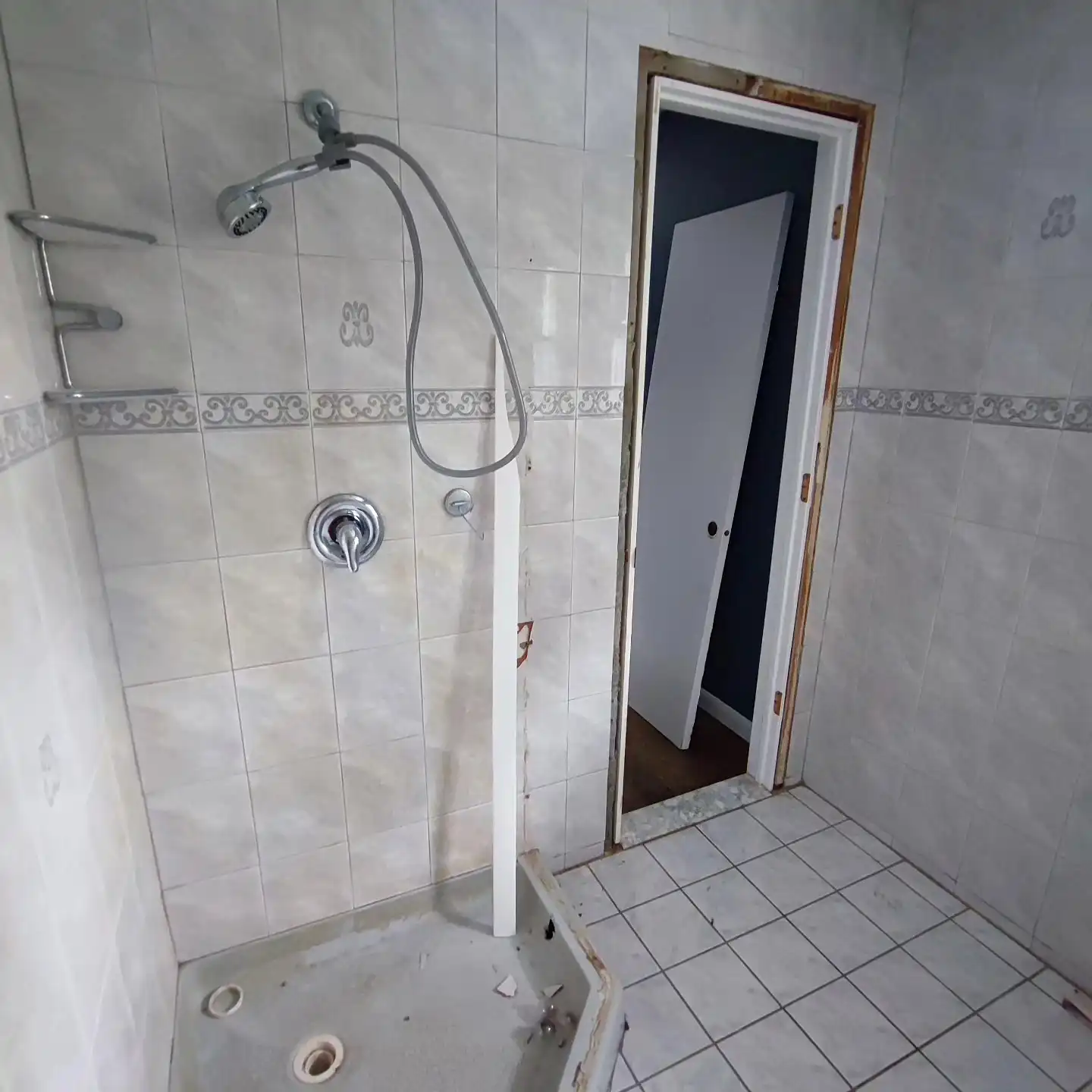 Original shower with white 4×4 tile, a blue border and a fixed shower head