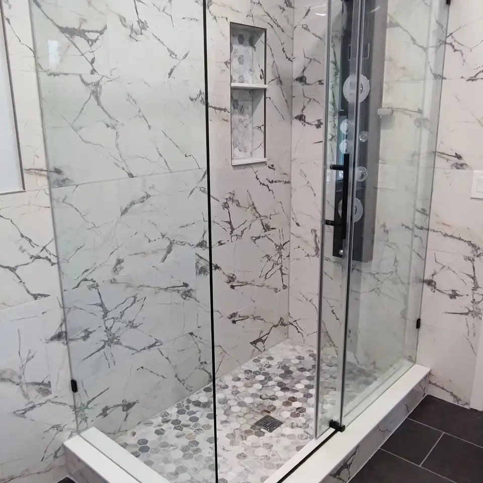 Glass shower with marble-look walls and a grey hexagon mosaic floor