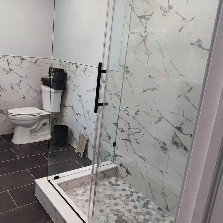 Shower, toilet and vanity in a row along the marble-look wainscot