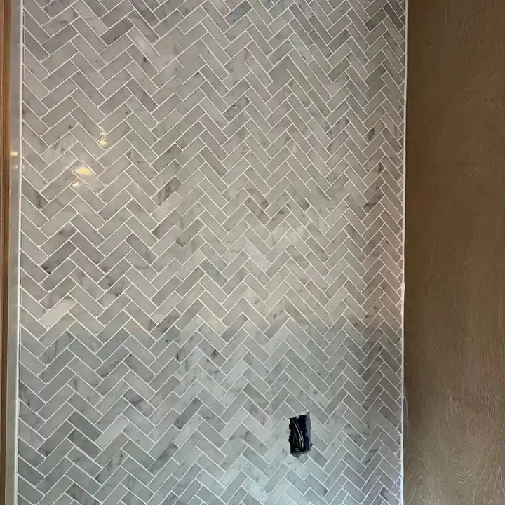 Close view of honed marble herringbone mosaic with the outlet cut flush