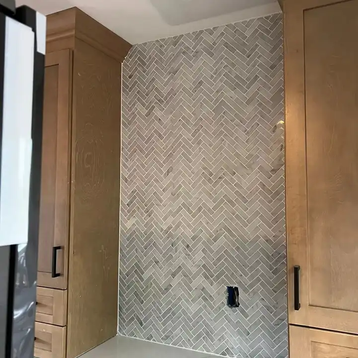Electrical outlet set flush into a marble herringbone mosaic