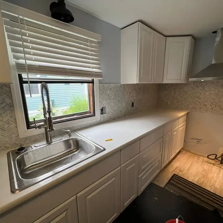 Stone mosaic backsplash around a kitchen window above the sink