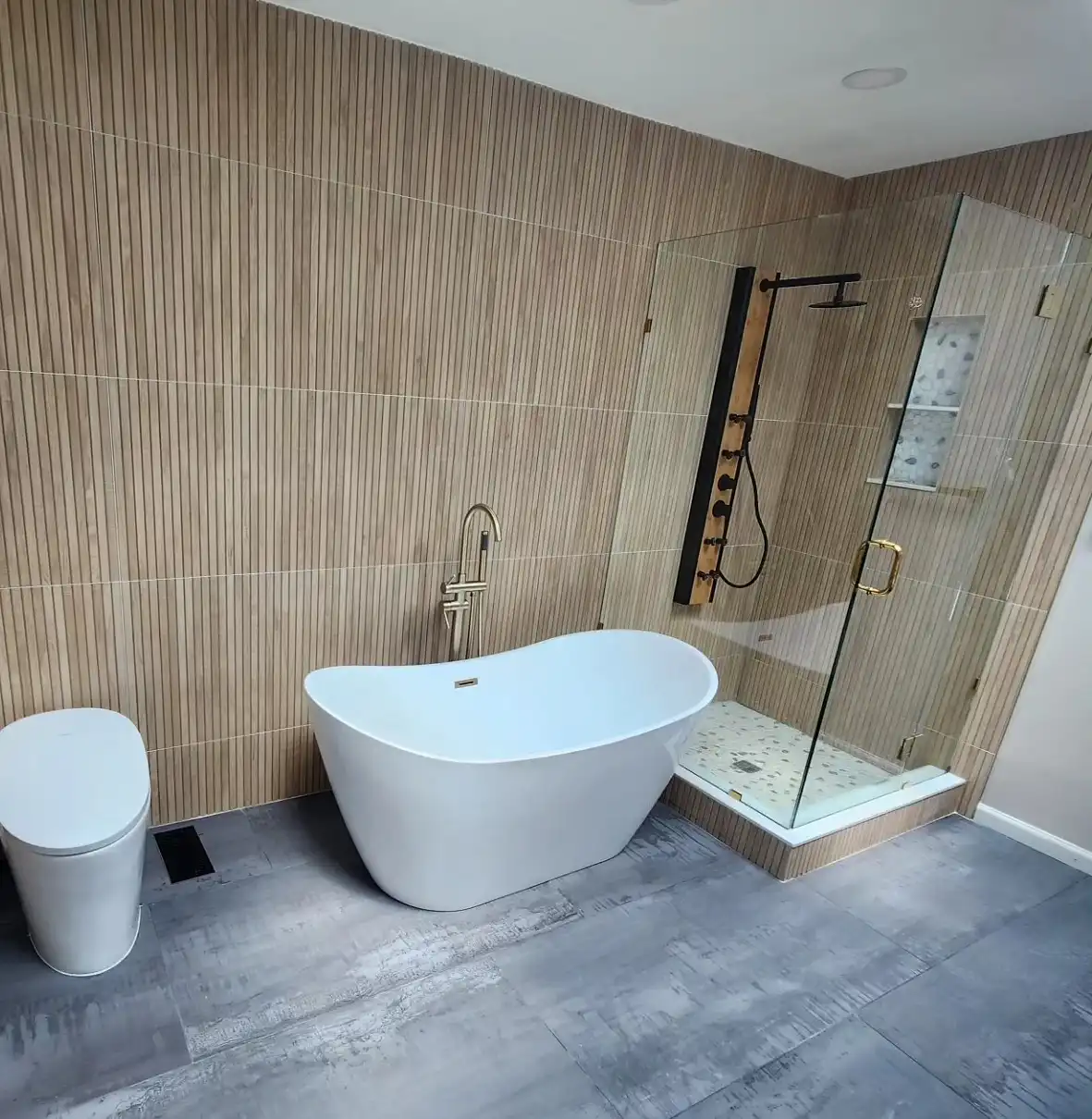 Freestanding tub against a wood-look porcelain wall beside a glass corner shower