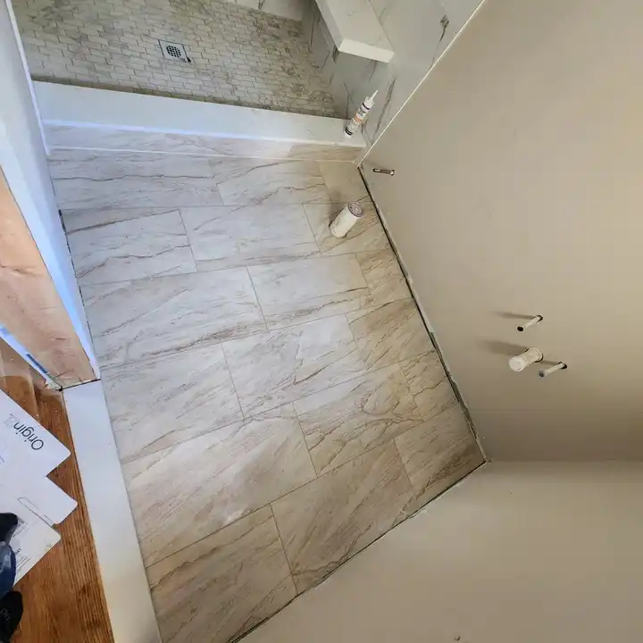 Plank floor tile running flush into the shower curb with a mosaic floor beyond