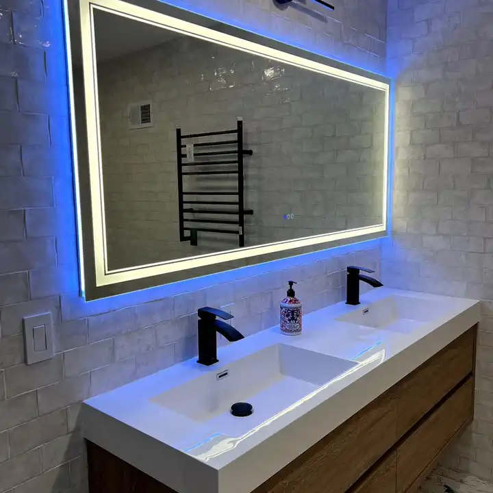 LED mirror above a double sink with a black towel warmer on white tile