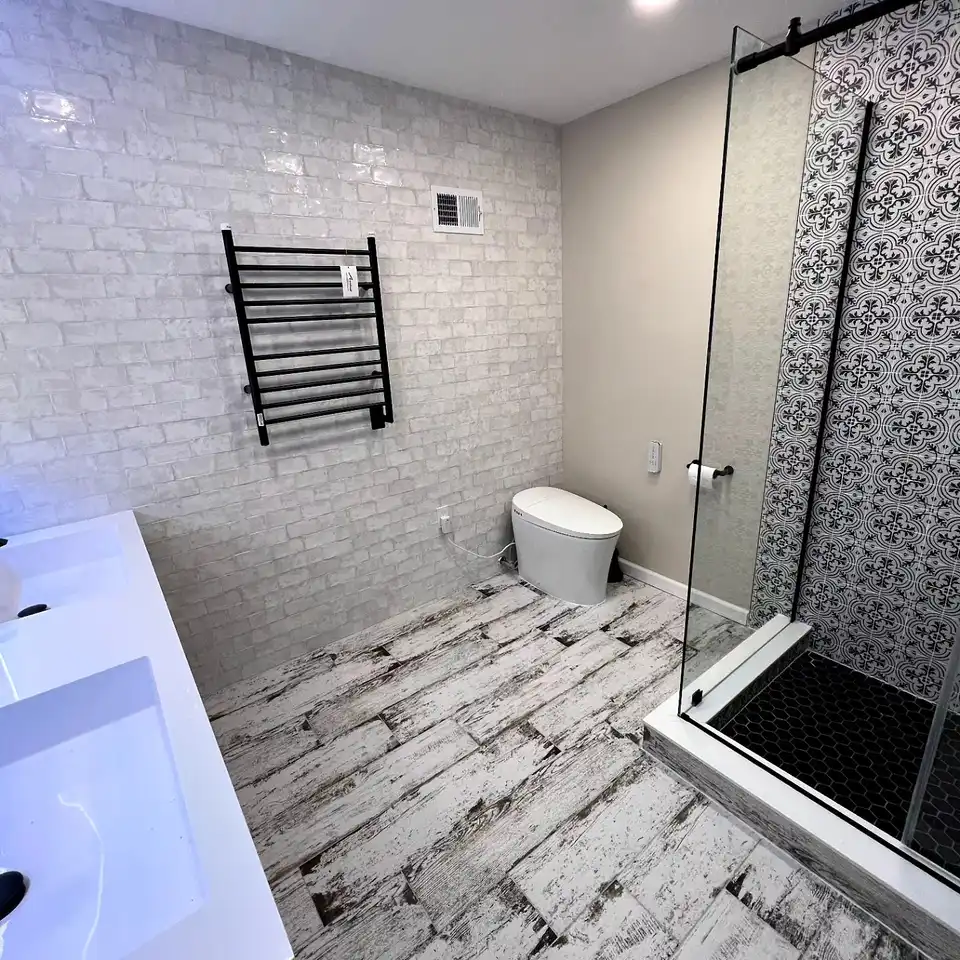 White handmade-look tile bathroom with a black towel warmer and a patterned shower
