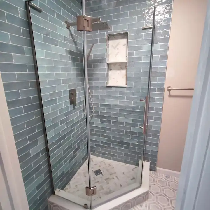 Green subway shower with a recessed niche, grey vanity and toilet beside it