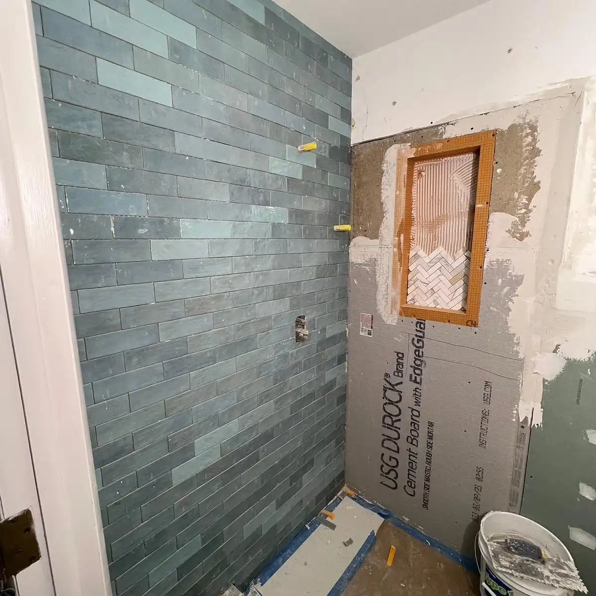 Shower walls half tiled in green subway on fresh backer board