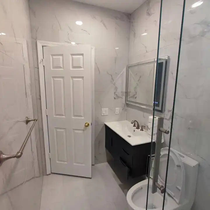Black vanity and toilet on a marble-look floor with the shower door open