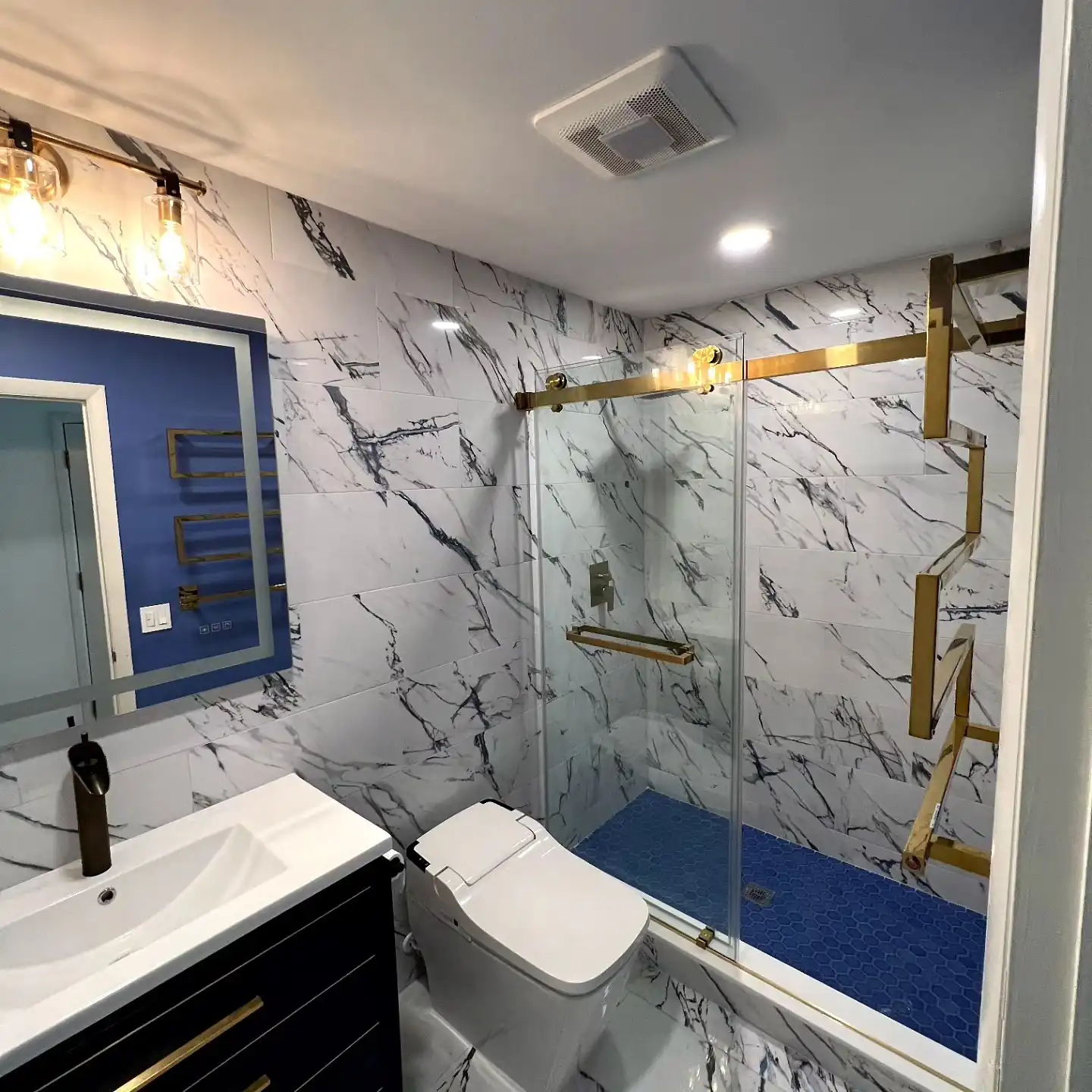 Marble-look bathroom with brushed gold shower door and towel warmer, navy vanity
