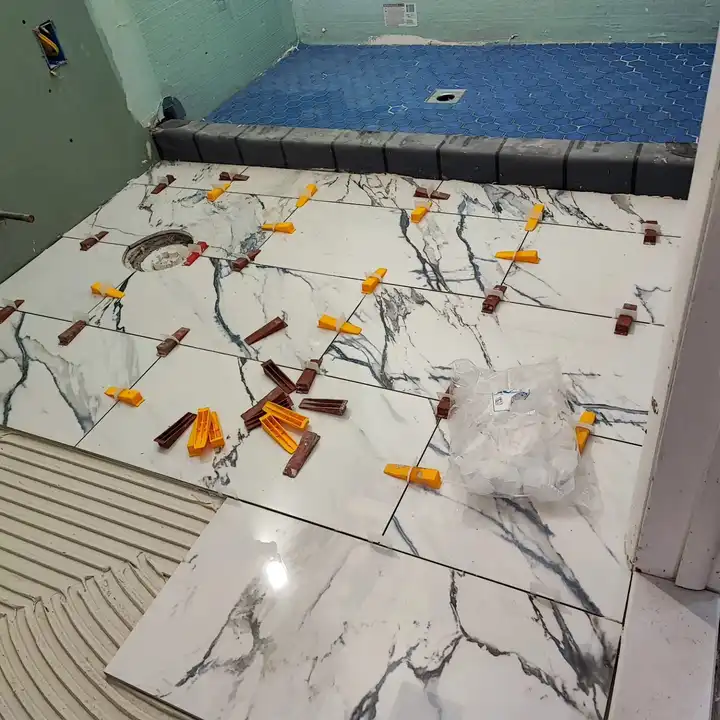 Marble-look floor tile being set with levelling clips, the layout centred on the room
