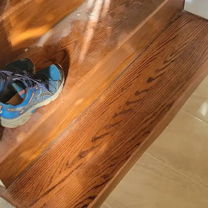 Plank tile meeting a wooden stair nosing flush at the bottom step